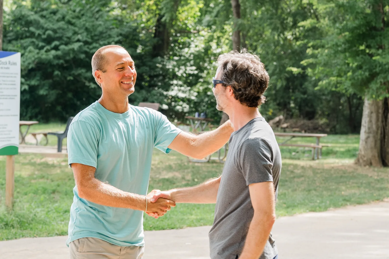 Therapist greeting a client with a handshake at a sunny trailhead
